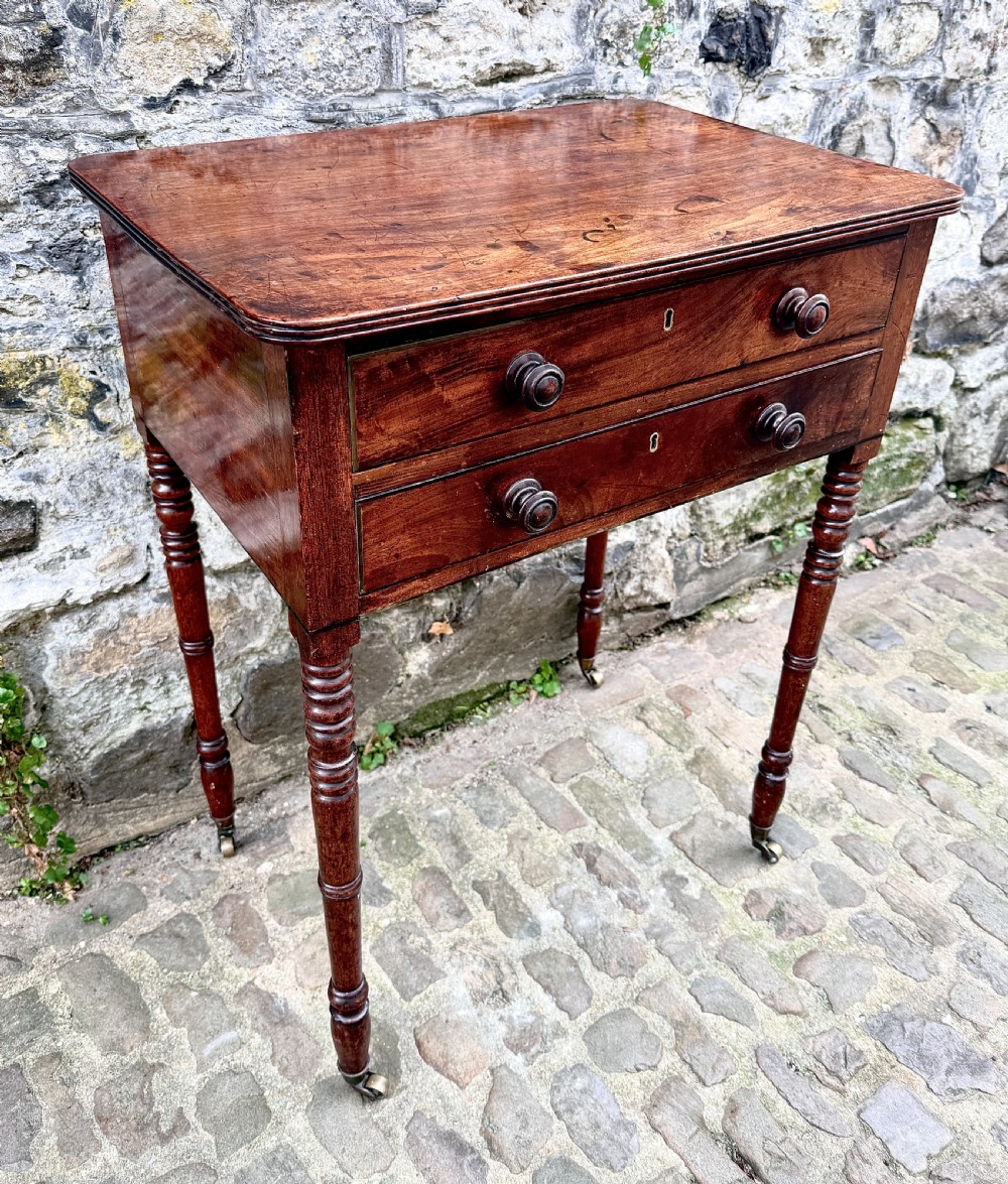 A Regency mahogany side table featuring two drawers with turned wooden handles, ring-turned legs, and brass castors. View III