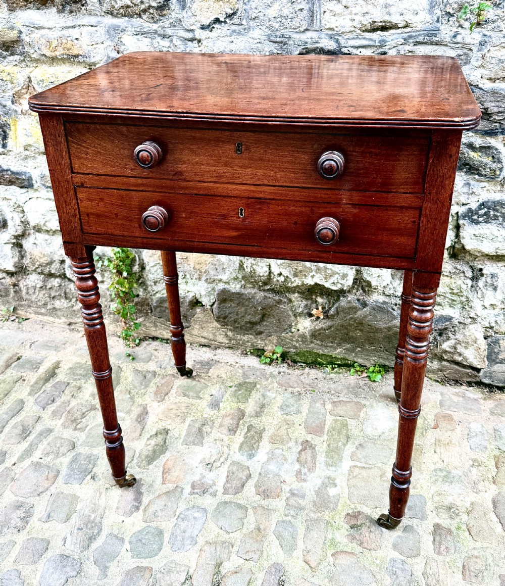 A Regency mahogany side table featuring two drawers with turned wooden handles, ring-turned legs, and brass castors. View VI