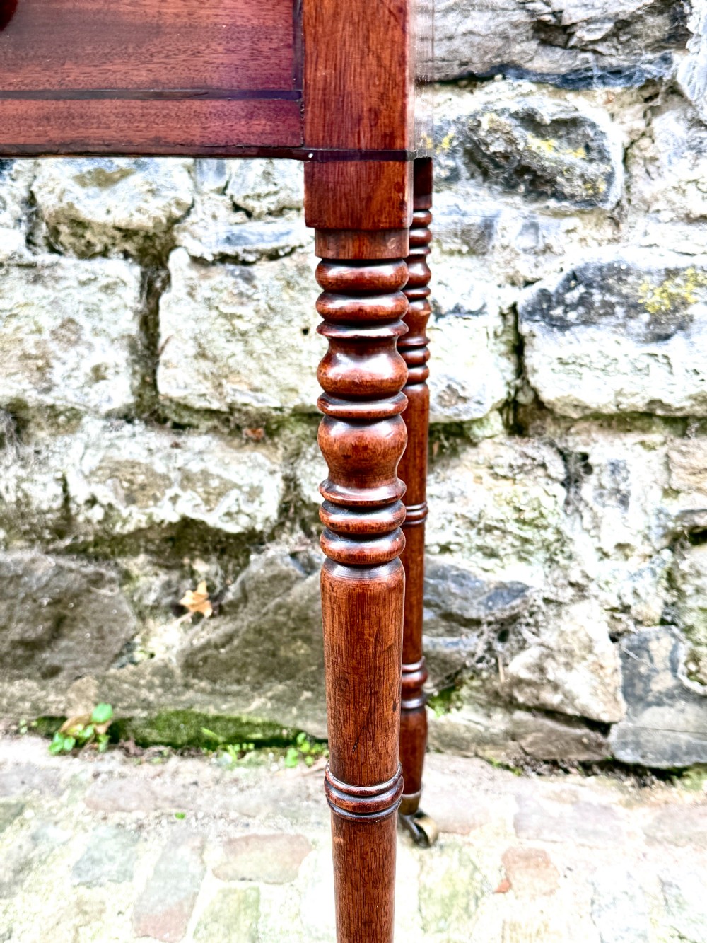 A Regency mahogany side table featuring two drawers with turned wooden handles, ring-turned legs, and brass castors. View VII