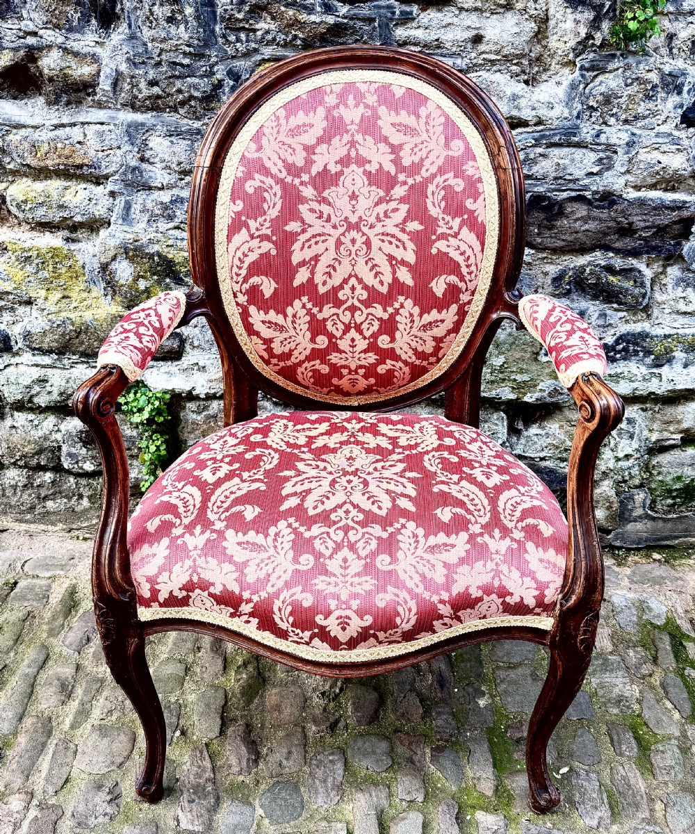 A French Louis XV style open-arm chair crafted from carved walnut with red and gold damask upholstery. View II