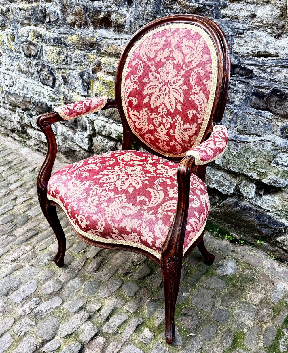 A French Louis XV style open-arm chair crafted from carved walnut with red and gold damask upholstery. View III