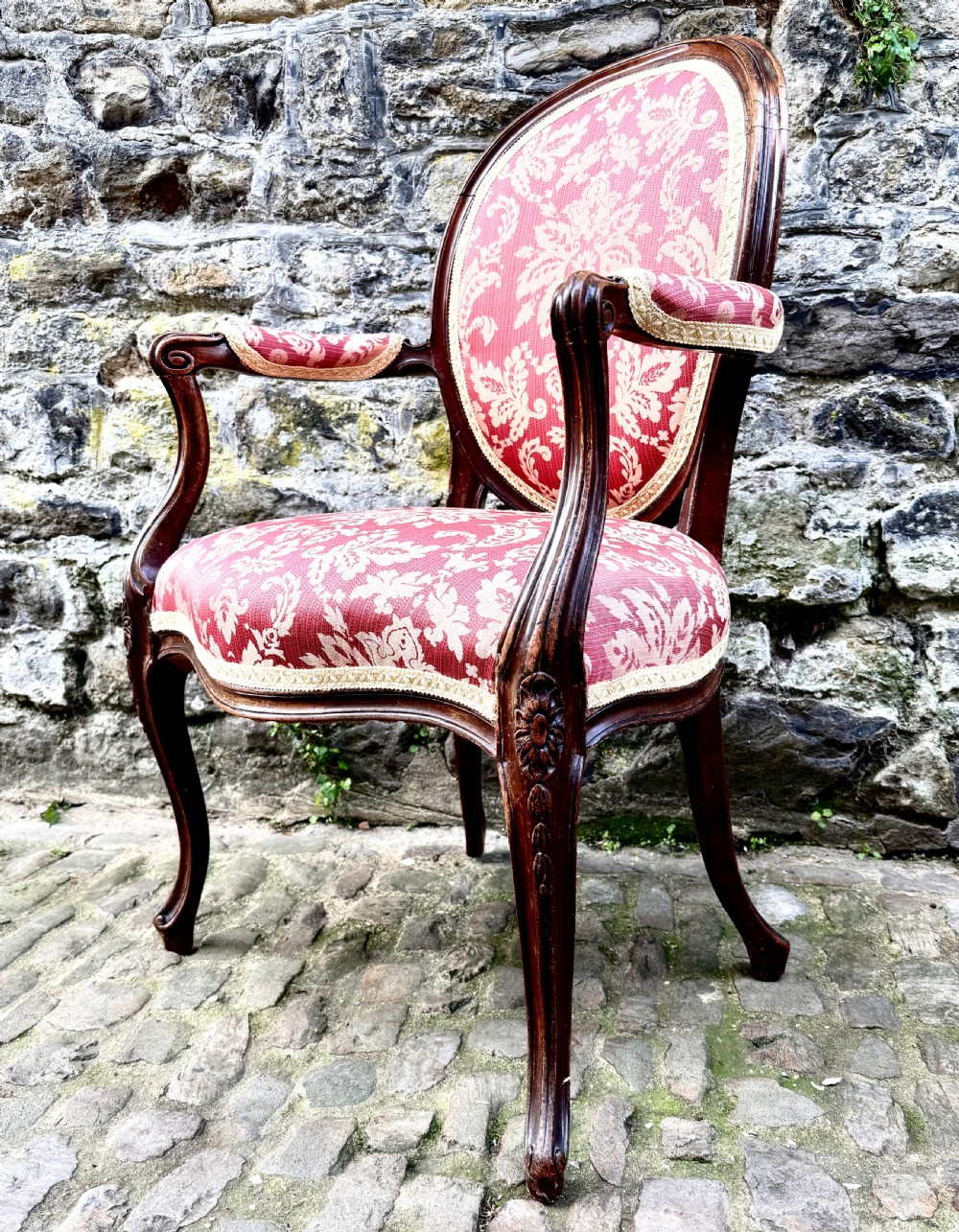 A French Louis XV style open-arm chair crafted from carved walnut with red and gold damask upholstery. View V