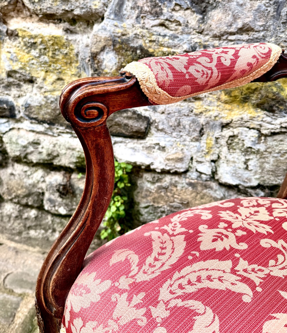 A French Louis XV style open-arm chair crafted from carved walnut with red and gold damask upholstery. View VI