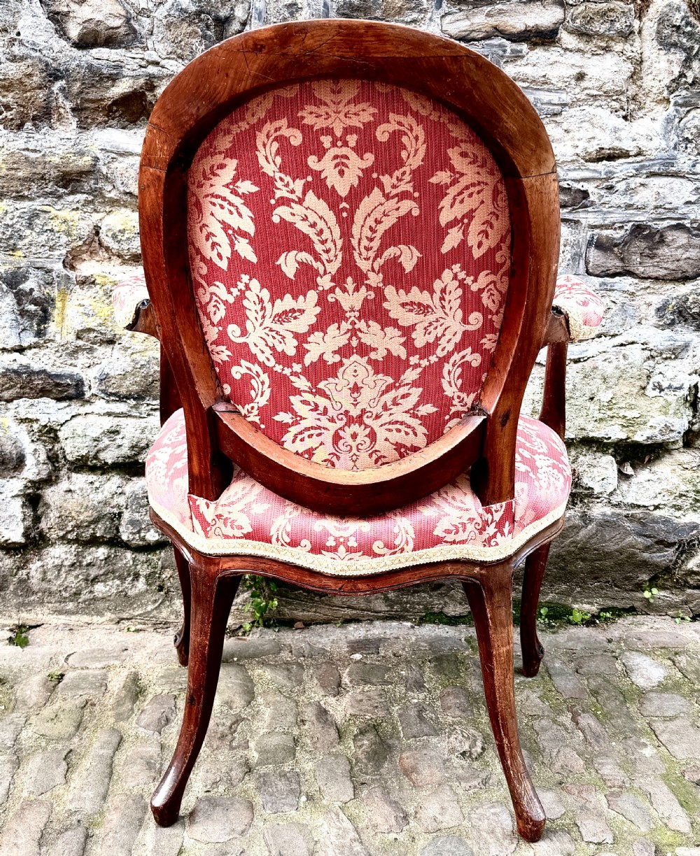 A French Louis XV style open-arm chair crafted from carved walnut with red and gold damask upholstery. View VIII