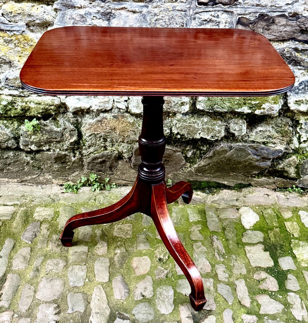 A Regency mahogany tripod side table featuring a rounded rectangular top supported by a turned central pedestal and three splayed legs.