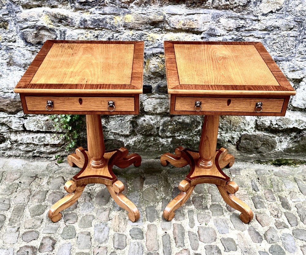 A pair of early 20th century ash pedestal side tables featuring single drawers with brass lion mask ring handles and quadruped scrolled bases. View II
