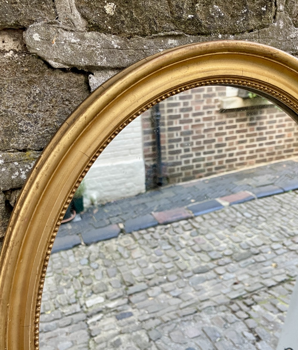 An oval mid-Victorian wall mirror featuring a gilded frame with a beaded inner border moulding. View III