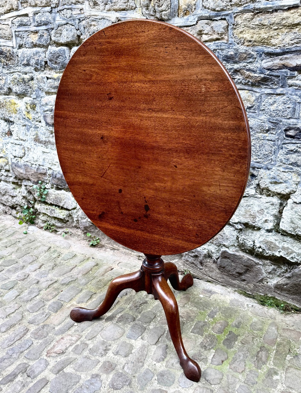 An 18th-century George III mahogany tripod table with a circular tilt top surface, turned column pedestal, and three cabriole legs. View II