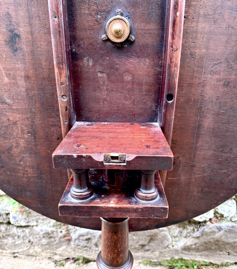 An 18th-century George III mahogany tripod table with a circular tilt top surface, turned column pedestal, and three cabriole legs. View IV