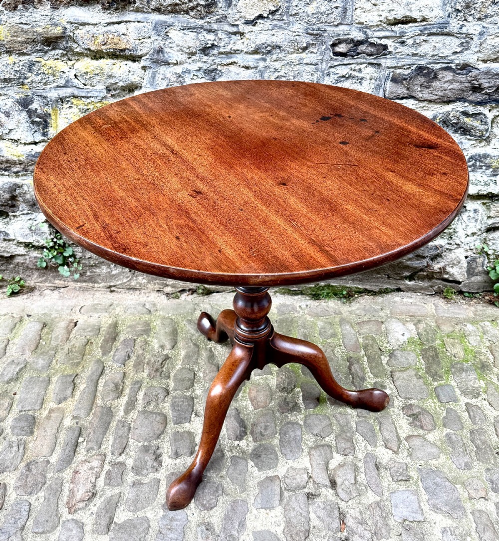 An 18th-century George III mahogany tripod table with a circular tilt top surface, turned column pedestal, and three cabriole legs. View V