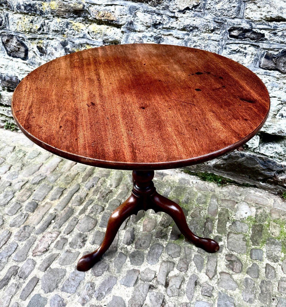 An 18th-century George III mahogany tripod table with a circular tilt top surface, turned column pedestal, and three cabriole legs. View VI