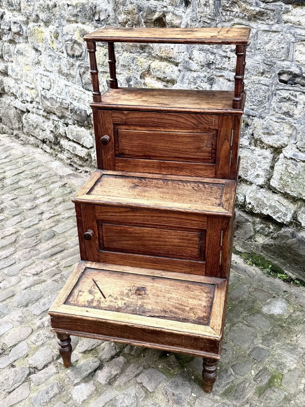 A flight of late Victorian oak library steps featuring three tiers, built-in cupboard doors, and turned support legs. View IV