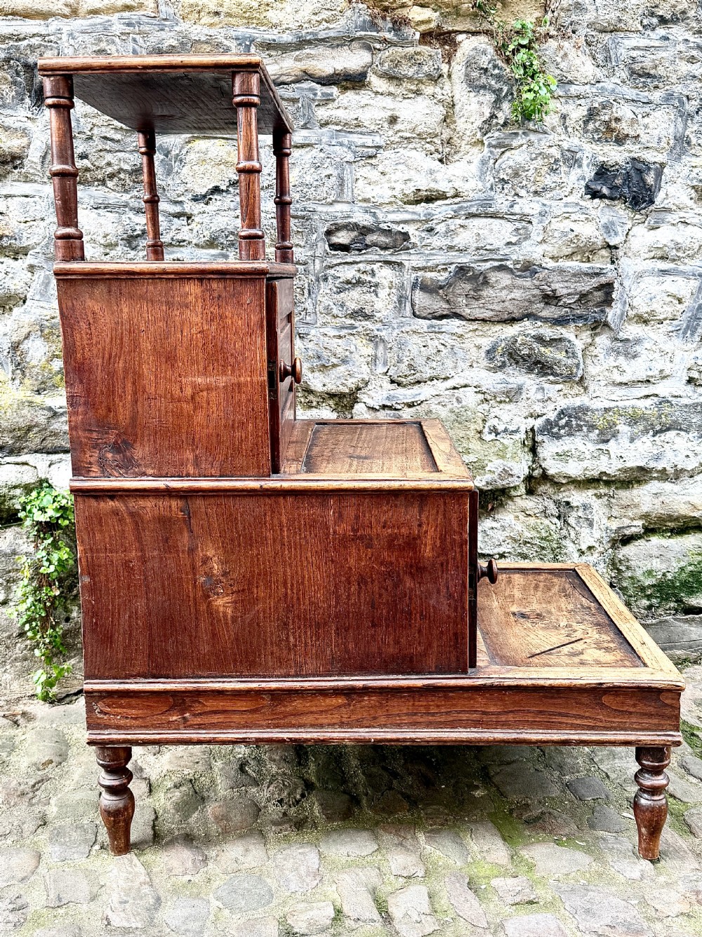 A flight of late Victorian oak library steps featuring three tiers, built-in cupboard doors, and turned support legs. View V