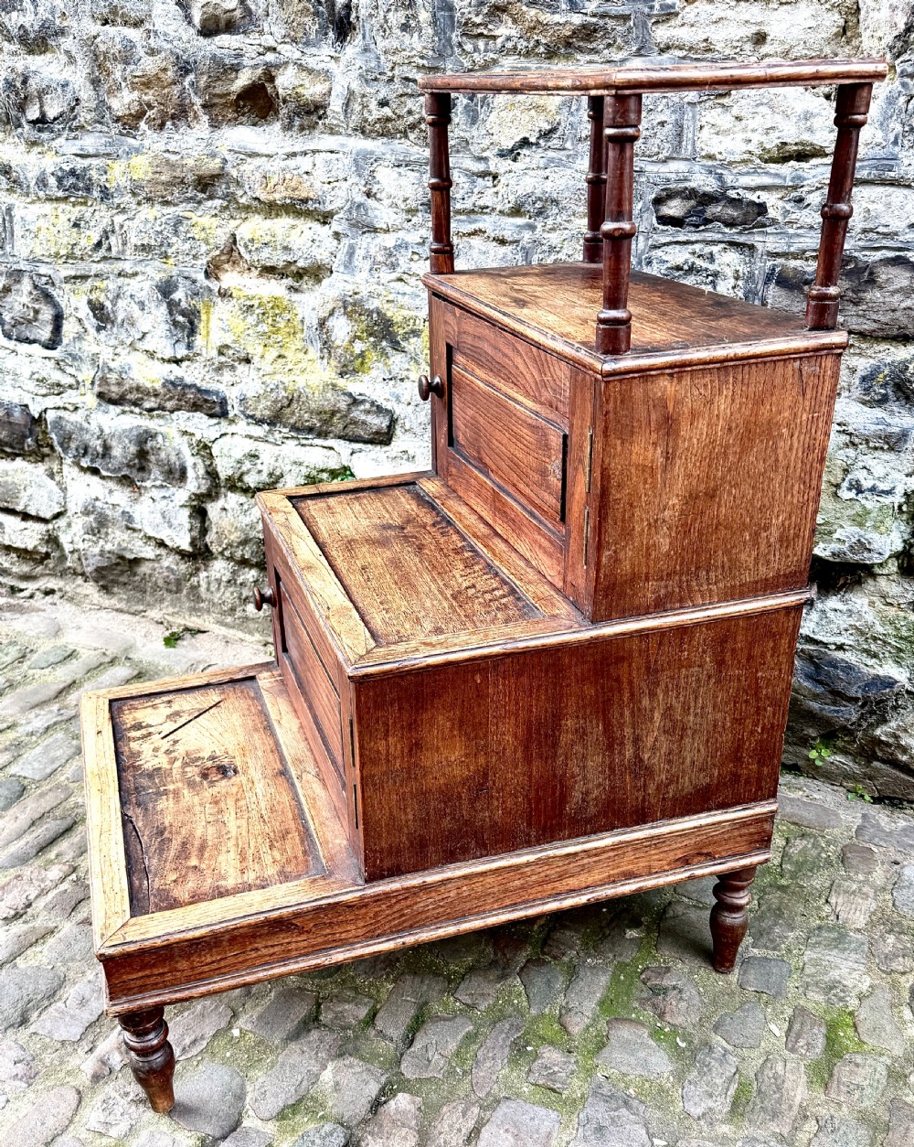 A flight of late Victorian oak library steps featuring three tiers, built-in cupboard doors, and turned support legs. View VII