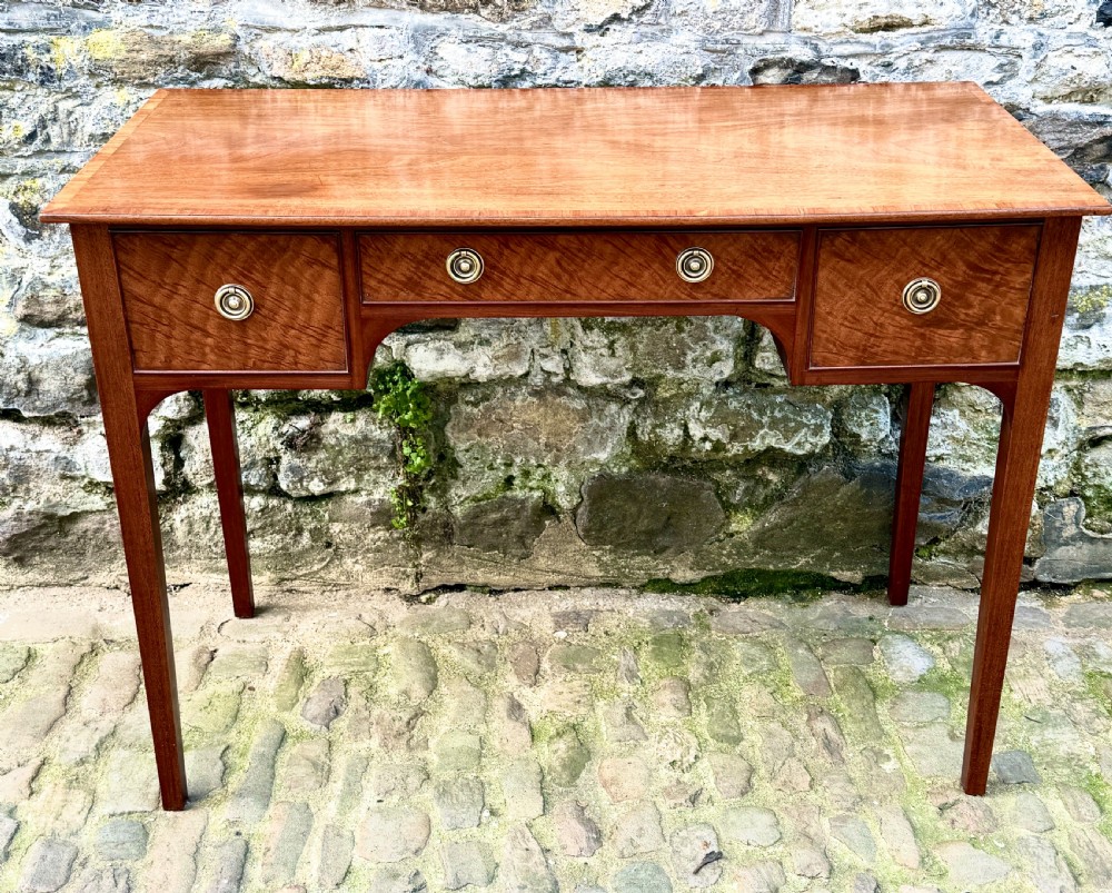 A Sheraton Revival mahogany writing table featuring a rectangular top, three drawers with brass ring drop handles, and slim tapered square legs. View III