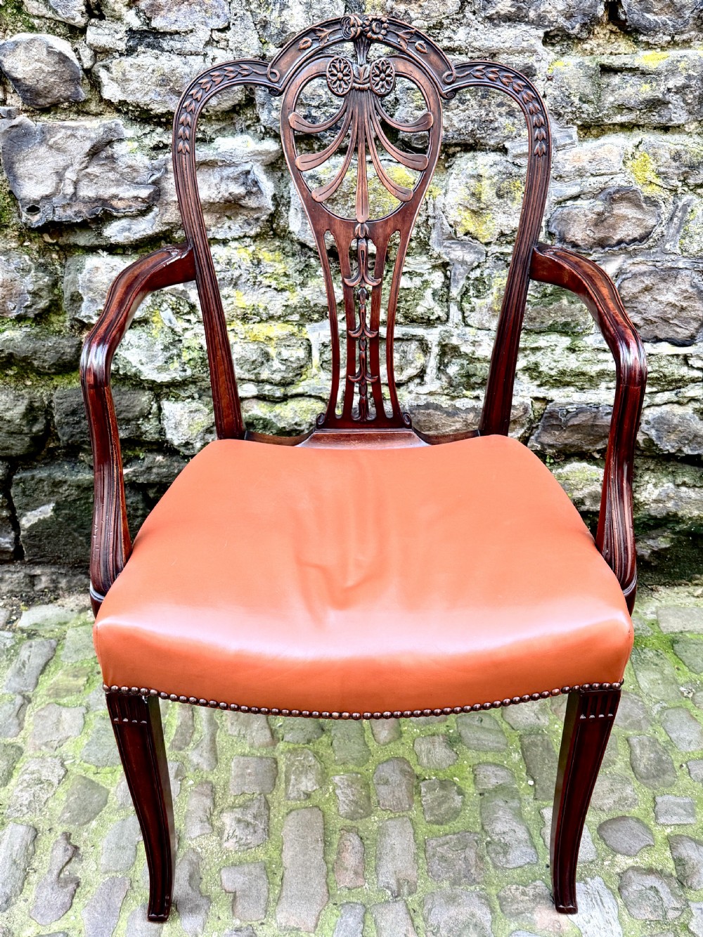 A set of eight carved mahogany dining chairs featuring openwork shield backs and terracotta leather seats secured with brass studs. View IX
