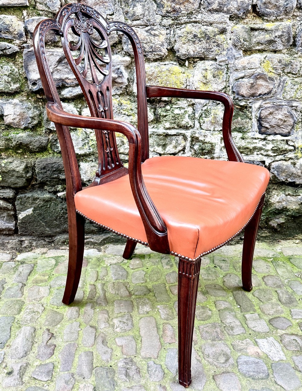 A set of eight carved mahogany dining chairs featuring openwork shield backs and terracotta leather seats secured with brass studs. View XI
