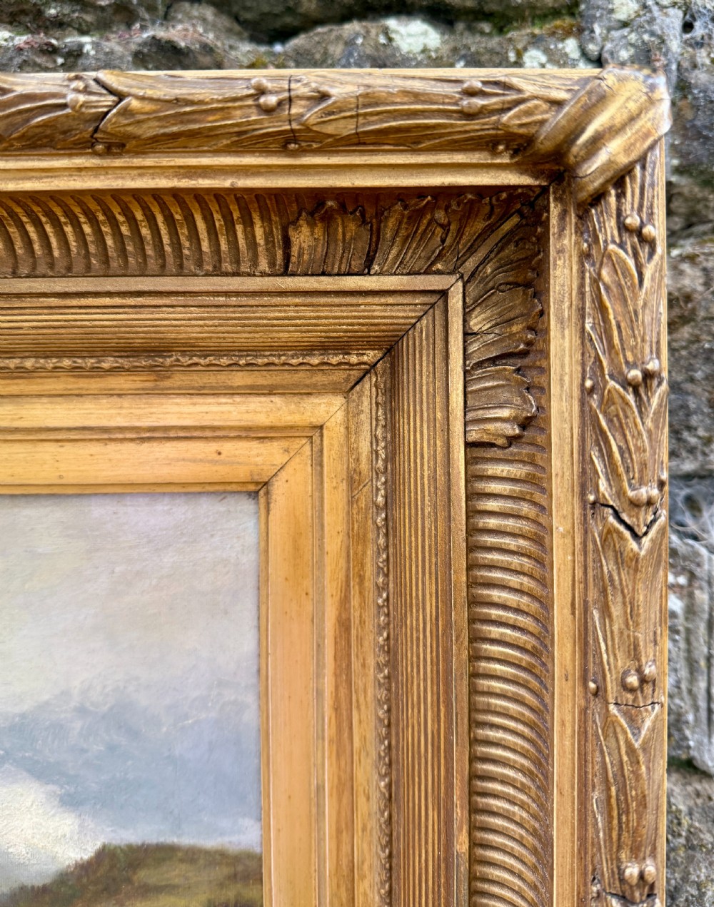 A Victorian oil painting depicting a calm Scottish loch with trees, rocky shorelines, and distant hills set inside a heavy moulded gilt wood frame. View VI
