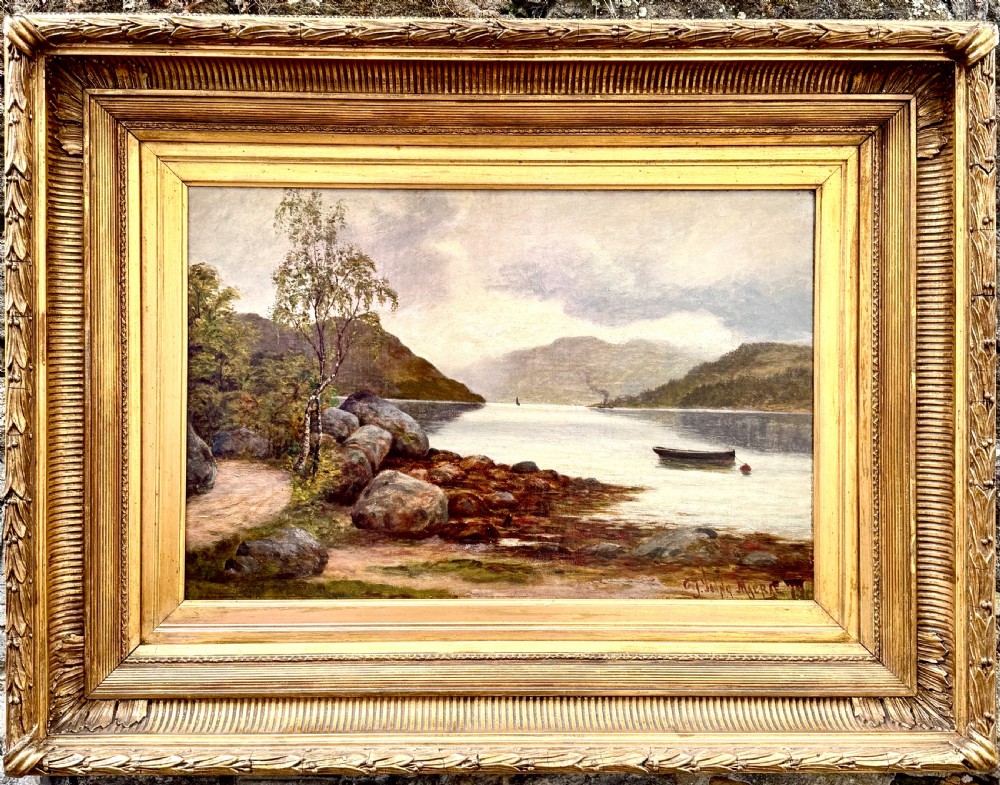 A Victorian oil painting depicting a calm Scottish loch with trees, rocky shorelines, and distant hills set inside a heavy moulded gilt wood frame. View VII