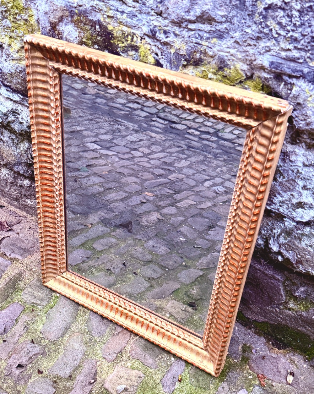 An early nineteenth-century rectangular French wall mirror featuring a carved gadrooned giltwood frame and a foxed glass plate. View IV