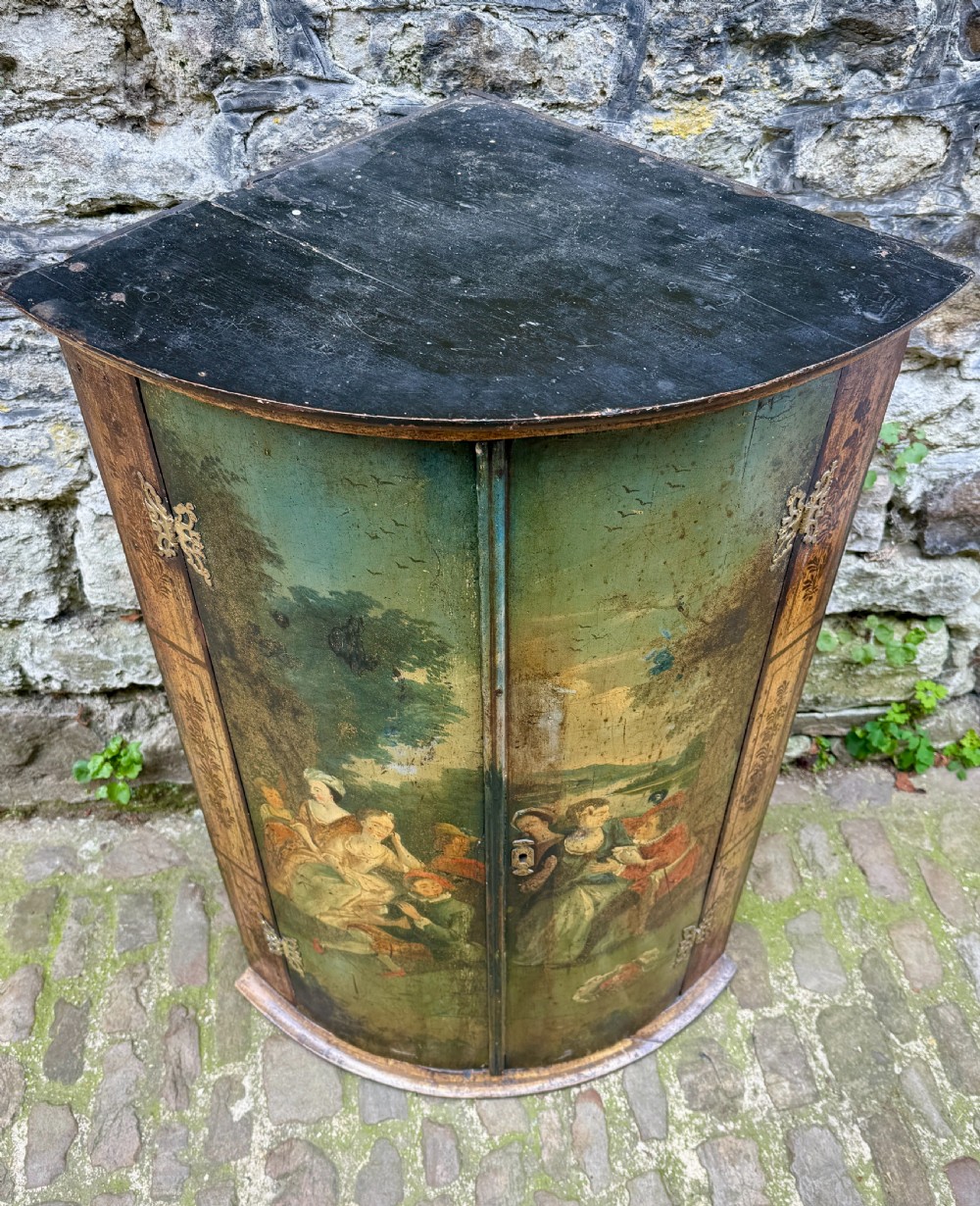 An eighteenth-century George II bowfront corner cupboard featuring two curved doors painted with a green pastoral scene and fitted with pierced brass hinges. View VI