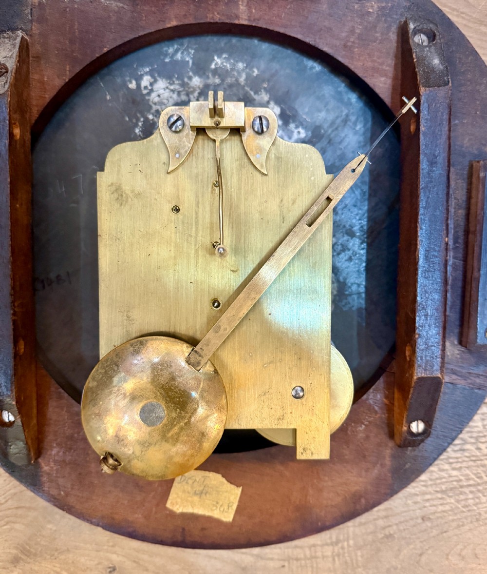 An early nineteenth-century circular English wall clock featuring a dark mahogany surround, brass-rimmed glass face, and a white dial with black Roman numerals. View III