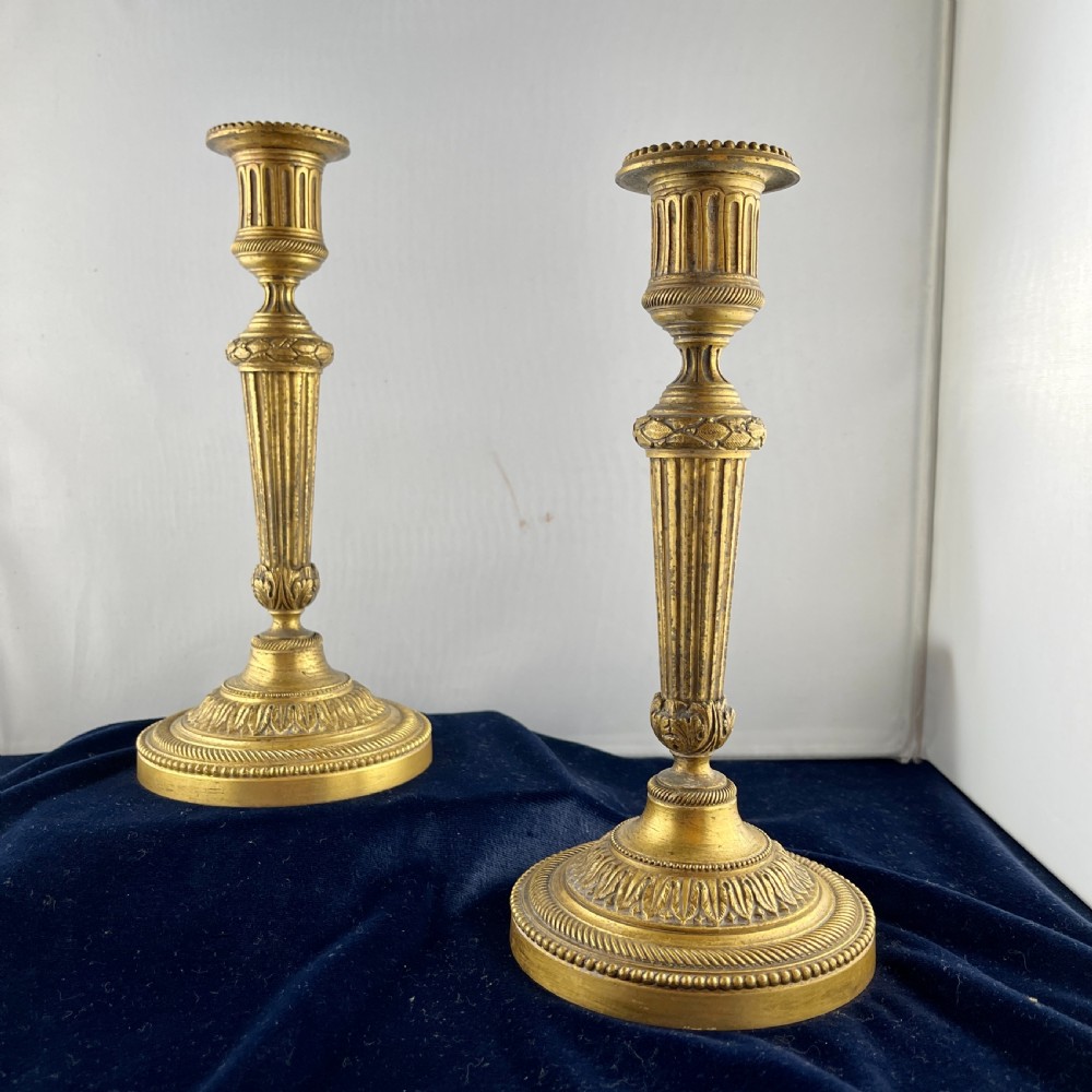 A pair of cast gilt bronze candlesticks featuring tapered fluted stems, acanthus leaf details, and circular beaded bases. View III