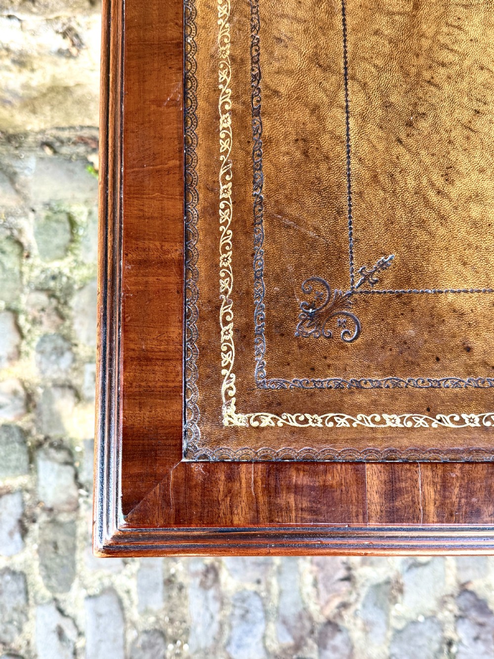 A George IV mahogany writing table featuring a gold-tooled brown leather top, five drawers, carved fan spandrels, and reeded legs on brass castors. View VI