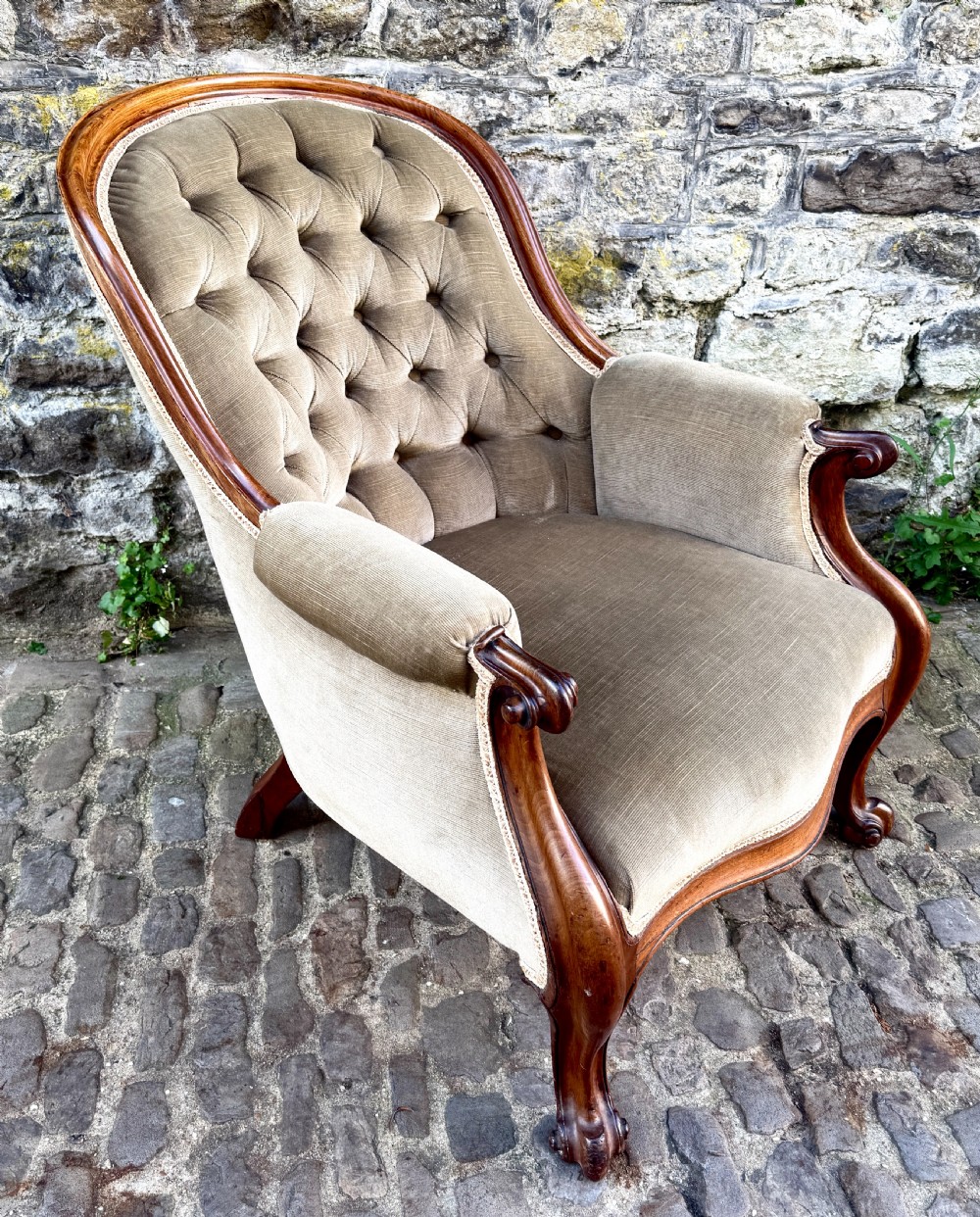 An Early Victorian walnut armchair featuring deep button-tufted olive green velvet upholstery, carved padded armrests, and cabriole front legs. View III