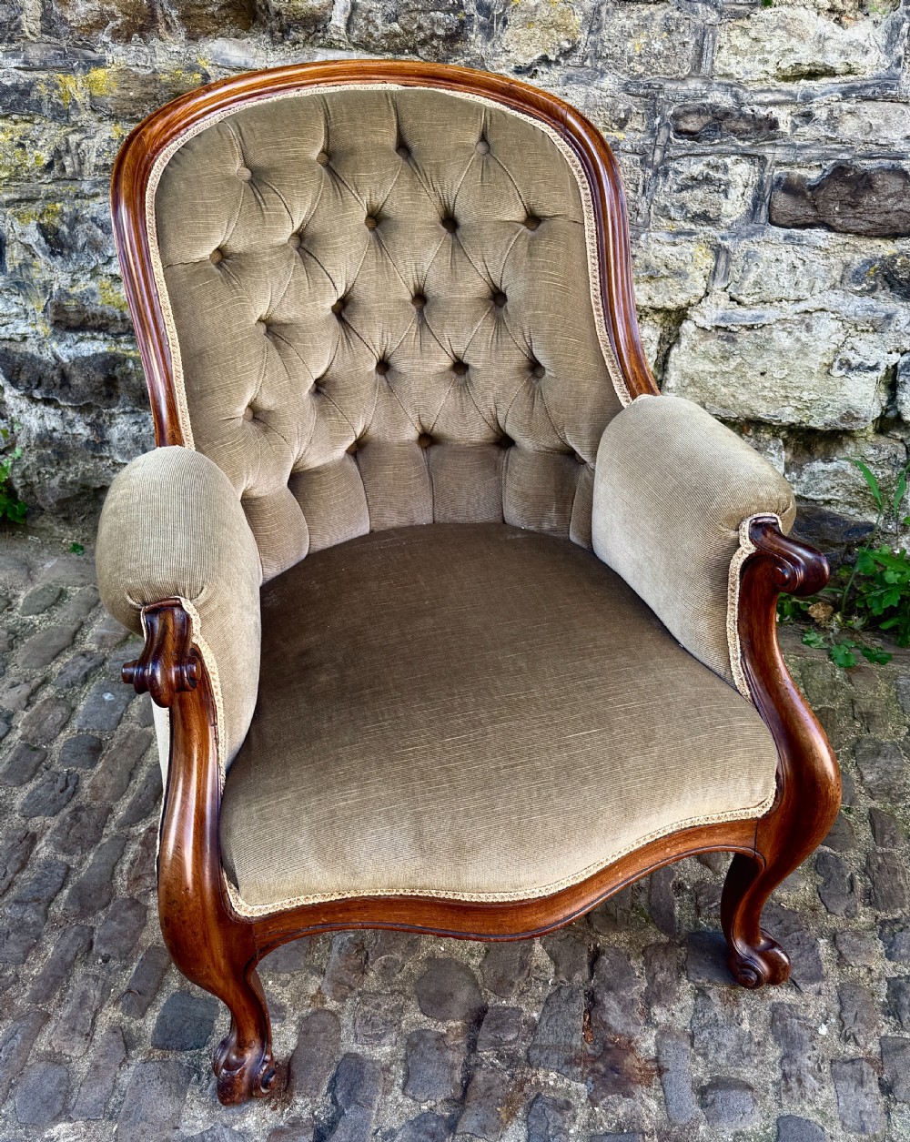 An Early Victorian walnut armchair featuring deep button-tufted olive green velvet upholstery, carved padded armrests, and cabriole front legs. View IX