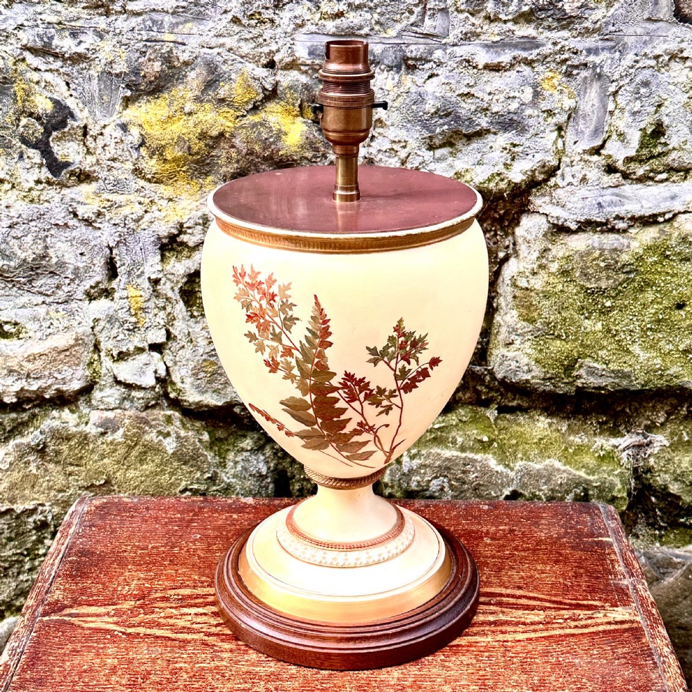 An urn-shaped cream porcelain table lamp decorated with painted fern foliage, mounted on a turned wooden base with a brass socket. View II