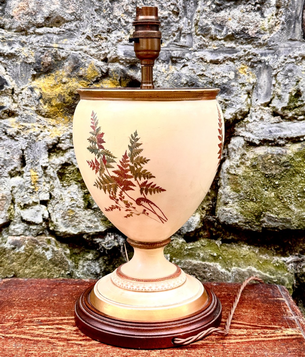 An urn-shaped cream porcelain table lamp decorated with painted fern foliage, mounted on a turned wooden base with a brass socket. View III