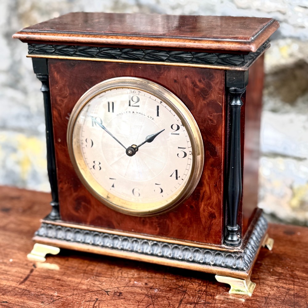 An early 20th-century rectangular mahogany and burr walnut mantel clock featuring ebonised side columns, a white circular dial signed Walker & Hall Ltd., and brass bracket feet. View III