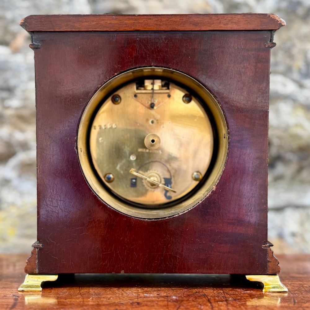 An early 20th-century rectangular mahogany and burr walnut mantel clock featuring ebonised side columns, a white circular dial signed Walker & Hall Ltd., and brass bracket feet. View V