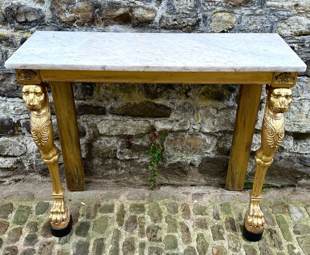 A Regency giltwood console table featuring a grey marble top supported by two carved lion monopodia front legs. View II