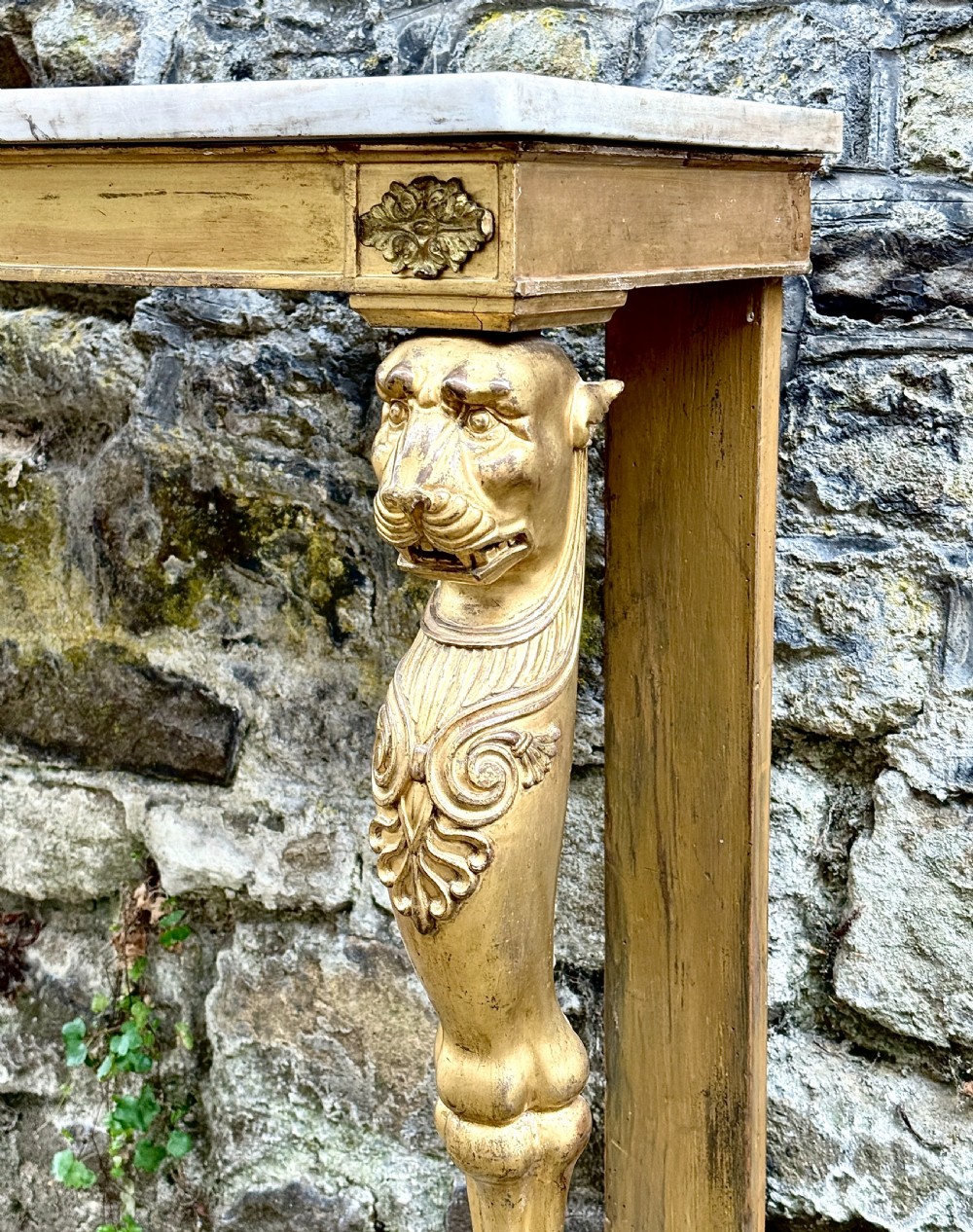 A Regency giltwood console table featuring a grey marble top supported by two carved lion monopodia front legs. View IV