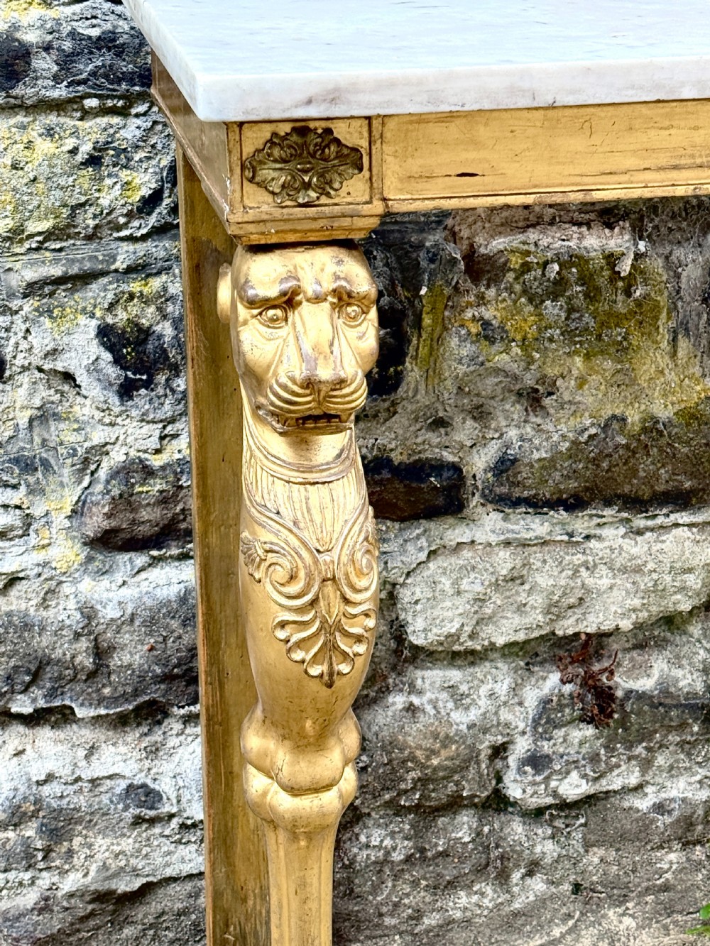 A Regency giltwood console table featuring a grey marble top supported by two carved lion monopodia front legs. View VI