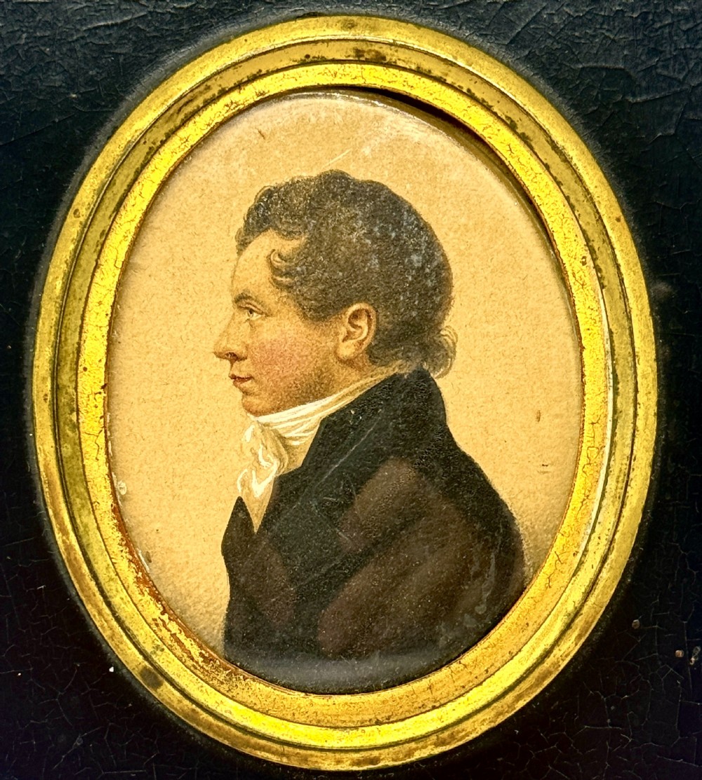 A Regency profile portrait miniature of a gentleman in a white cravat, set within an oval gilt bezel and rectangular black ebonised frame. View II