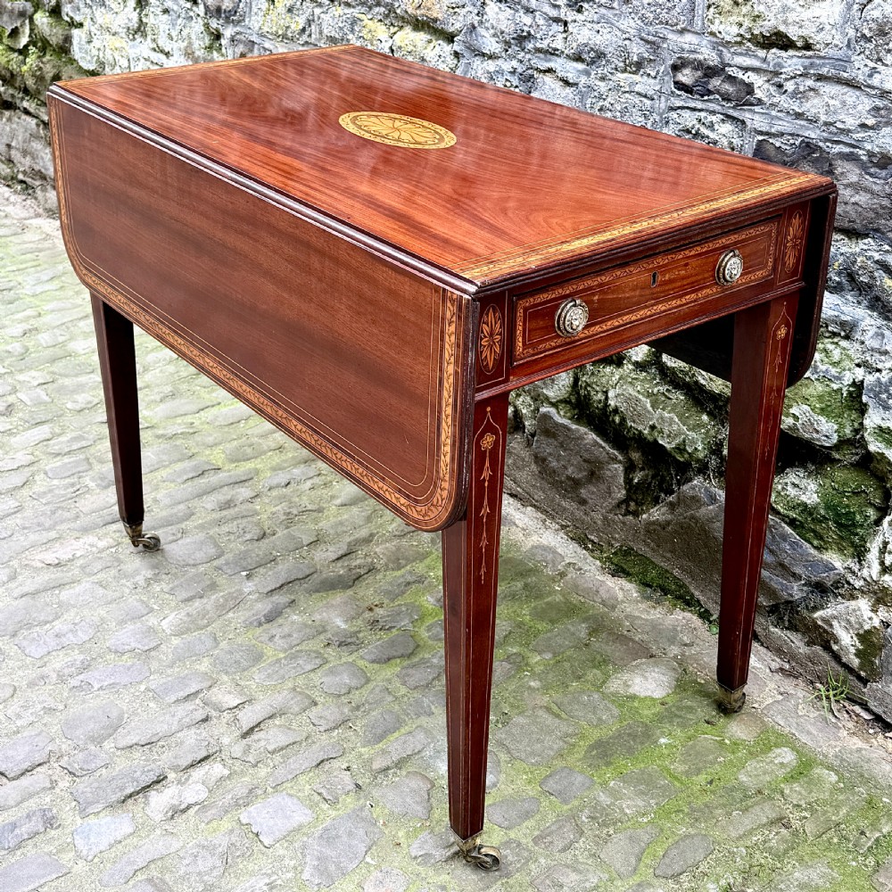 A George III mahogany Pembroke table with satinwood inlay, tapered square legs, and brass castors.