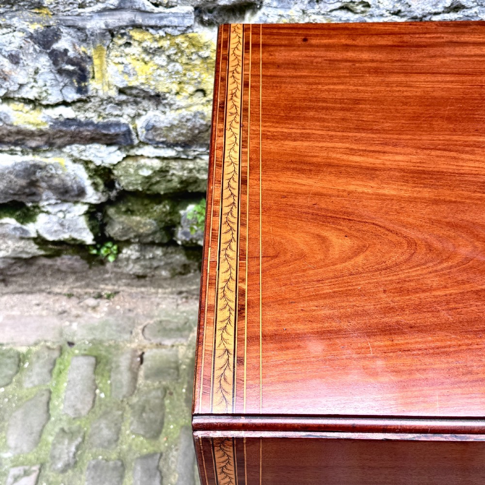 A George III mahogany Pembroke table with satinwood inlay, tapered square legs, and brass castors. View III
