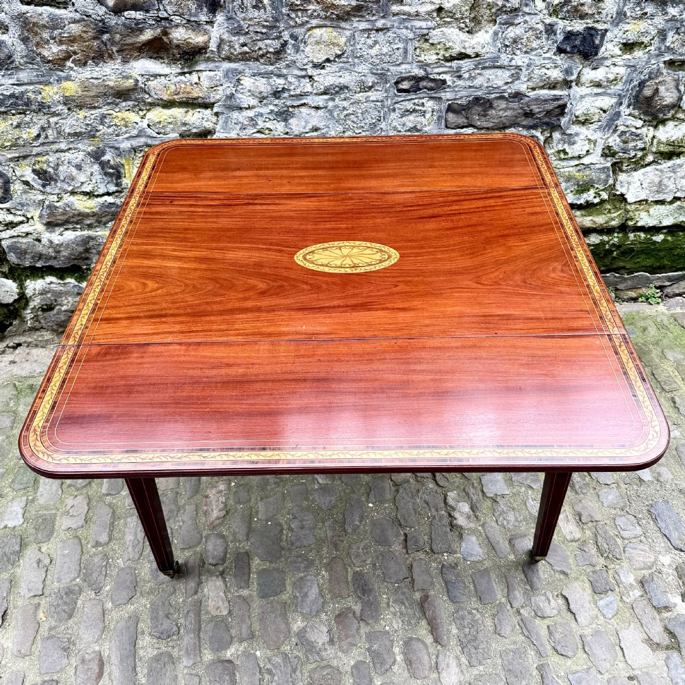 A George III mahogany Pembroke table with satinwood inlay, tapered square legs, and brass castors. View V