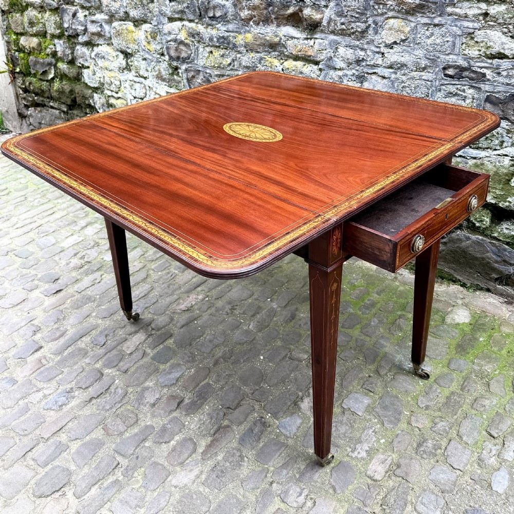 A George III mahogany Pembroke table with satinwood inlay, tapered square legs, and brass castors. View VI