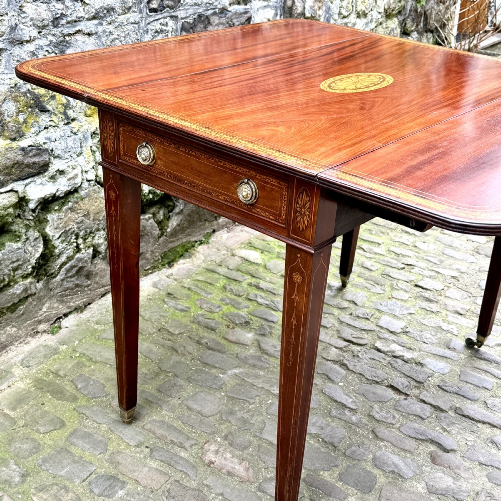 A George III mahogany Pembroke table with satinwood inlay, tapered square legs, and brass castors. View X