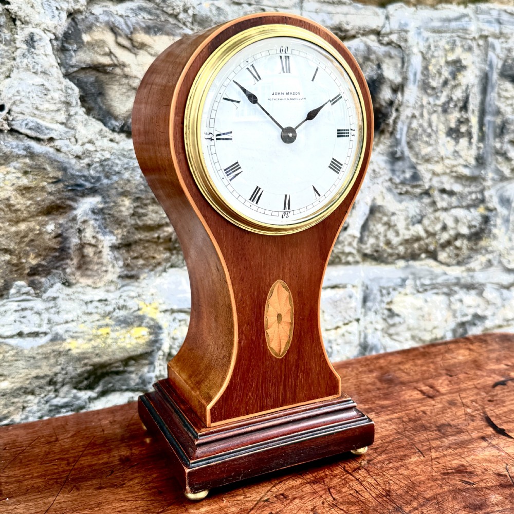 An Edwardian mahogany balloon-shaped mantel clock featuring a circular dial with Roman numerals and central marquetry inlay on a stepped base. View III