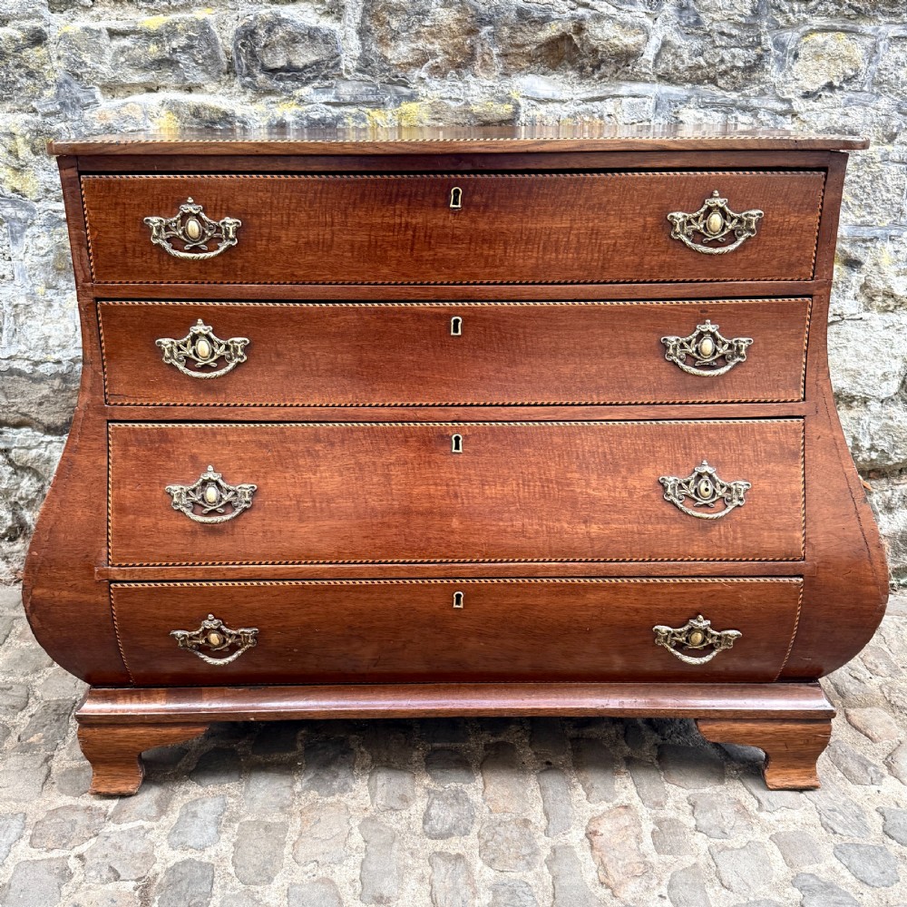 A late 18th-century Dutch mahogany chest of drawers featuring a shaped bombee profile, four long drawers with decorative brass handles, and bracket feet.