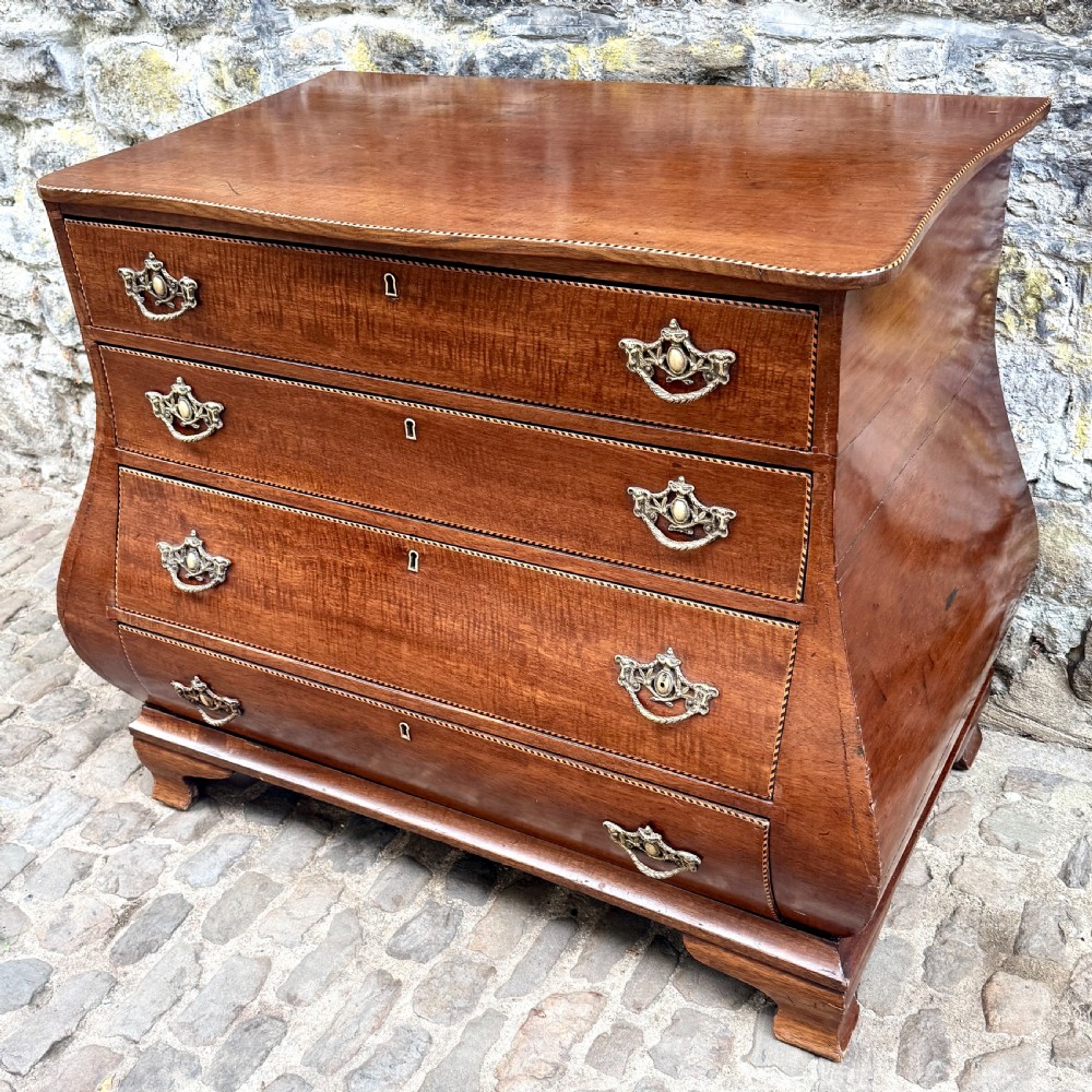 A late 18th-century Dutch mahogany chest of drawers featuring a shaped bombee profile, four long drawers with decorative brass handles, and bracket feet. View III
