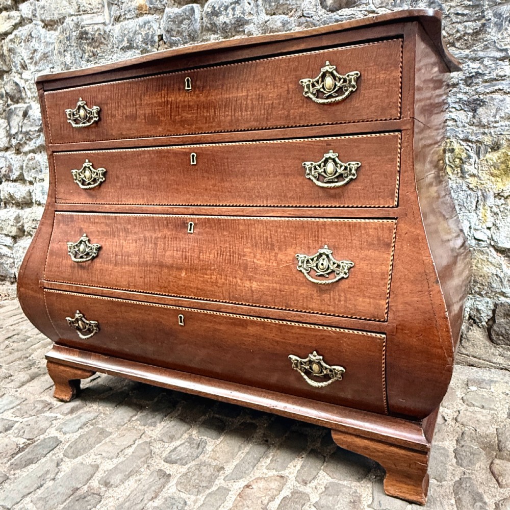 A late 18th-century Dutch mahogany chest of drawers featuring a shaped bombee profile, four long drawers with decorative brass handles, and bracket feet. View VIII