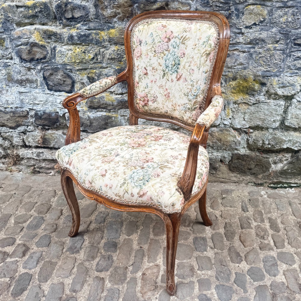 A Louis XV French provincial wooden armchair with carved cabriole legs and floral tapestry upholstery across the seat, backrest, and armrests. View II
