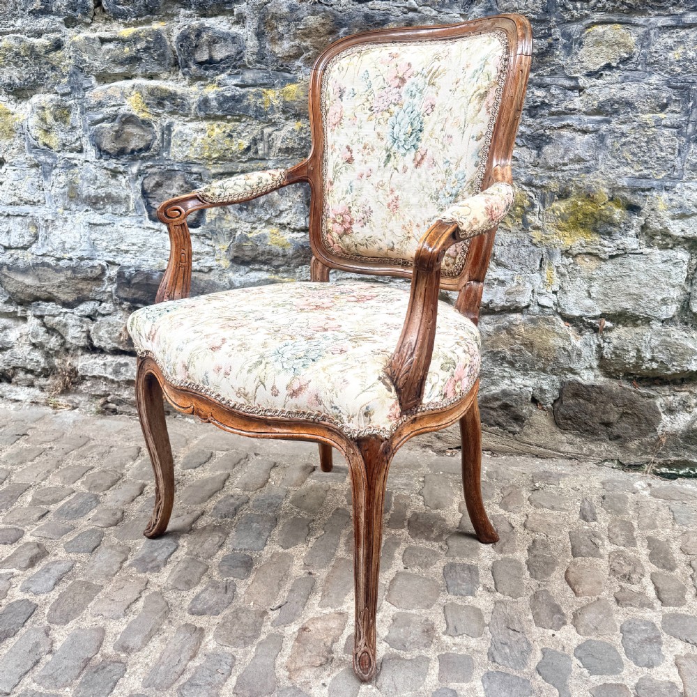 A Louis XV French provincial wooden armchair with carved cabriole legs and floral tapestry upholstery across the seat, backrest, and armrests. View III