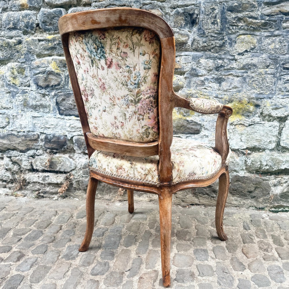 A Louis XV French provincial wooden armchair with carved cabriole legs and floral tapestry upholstery across the seat, backrest, and armrests. View V